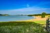 The grassy shore and the shoreline of Rutland Water, a large reservoir in Leicestershire.