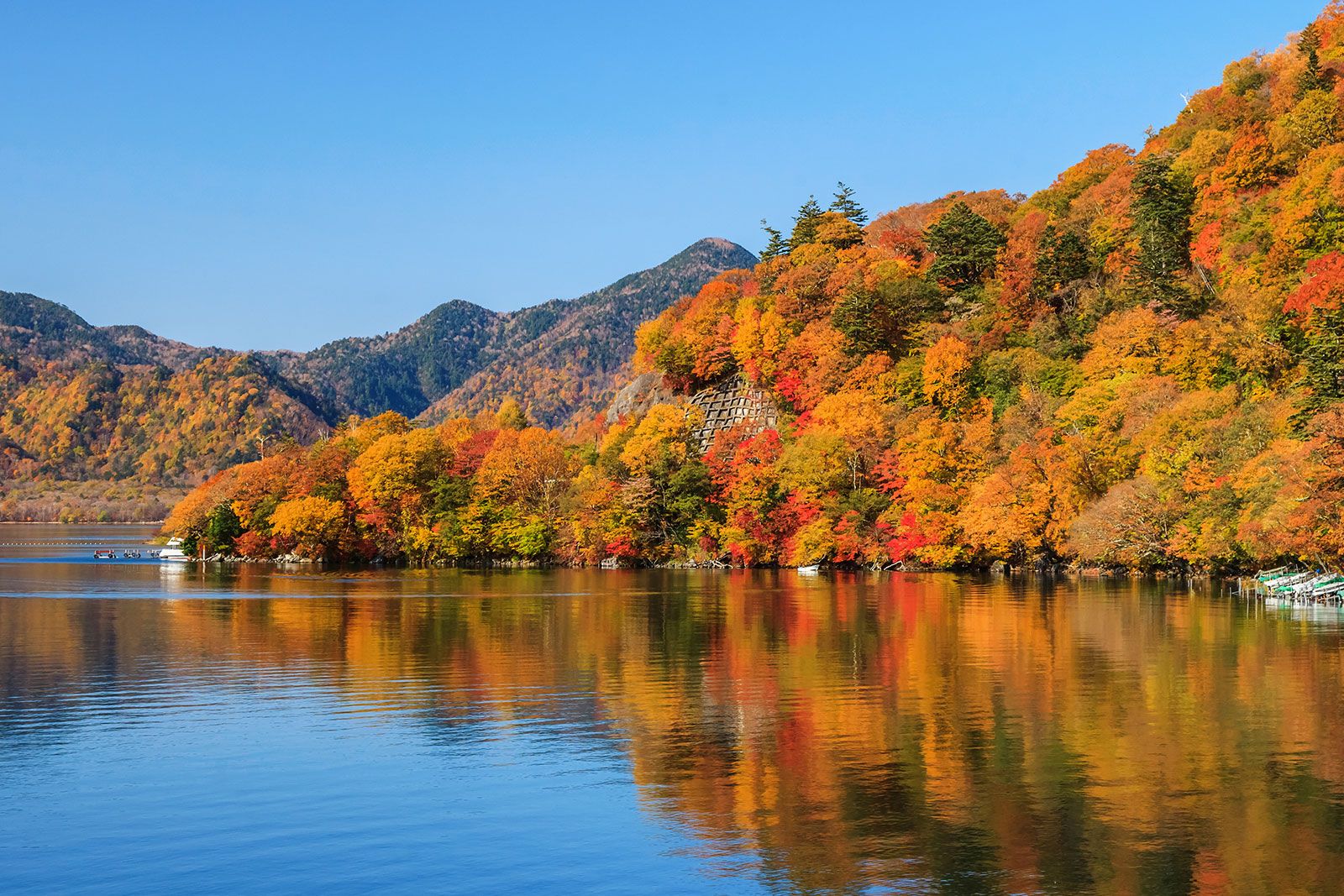 A lake with mountain covered in trees in autumn.