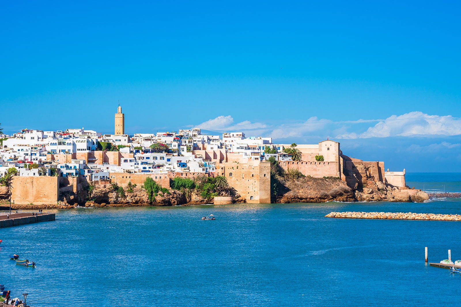 A scenic view of a city with white buildings surrounded by a castle on a coastline.