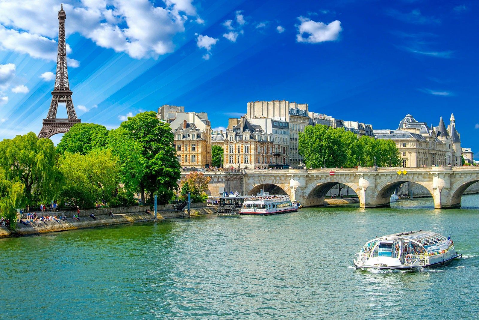 Eiffel Tower, green trees, a sightseeing boat on the Seine.