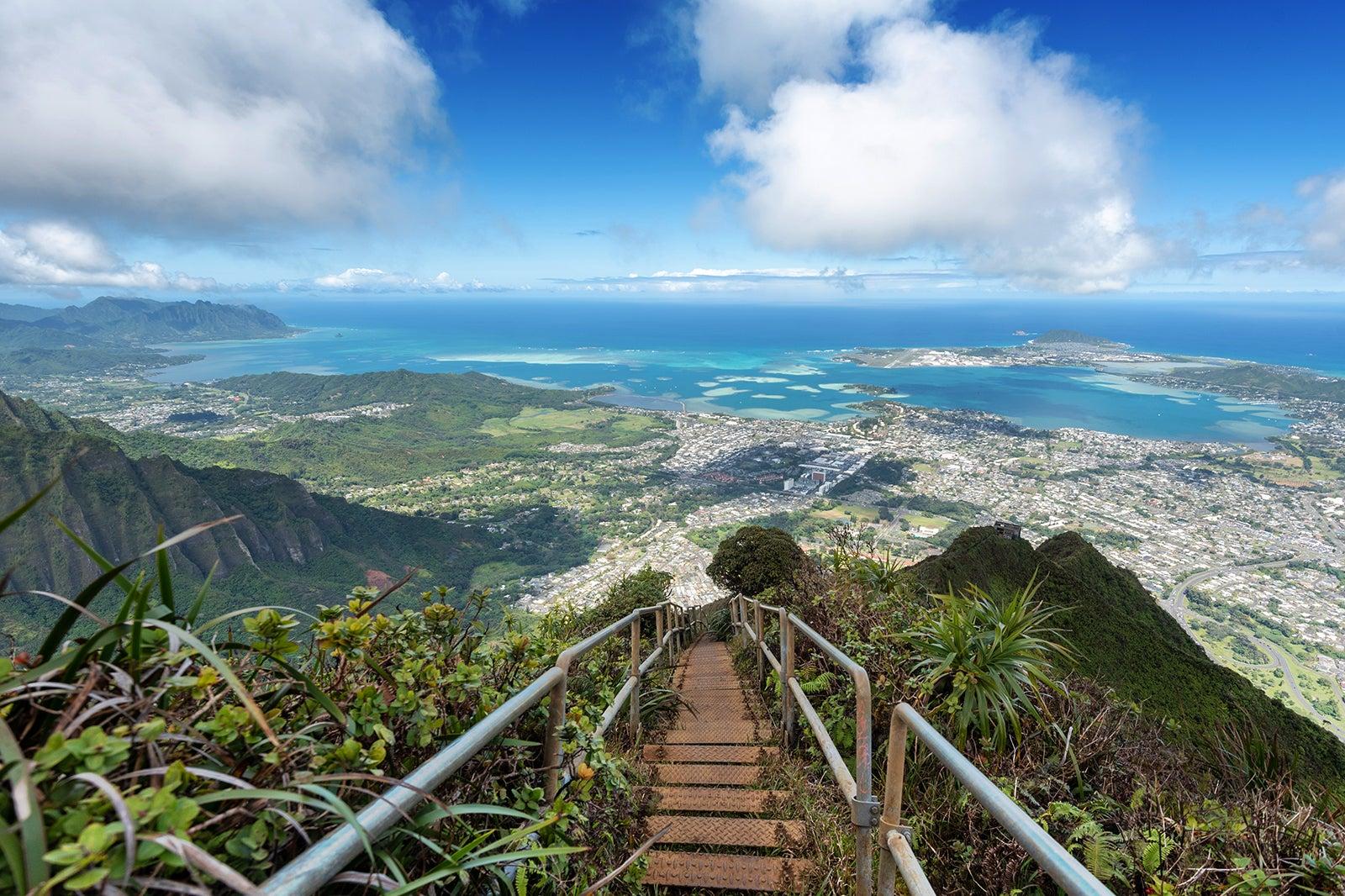 Long path with steps and a railing overlooking ocean with blue sky and puffy white clouds.