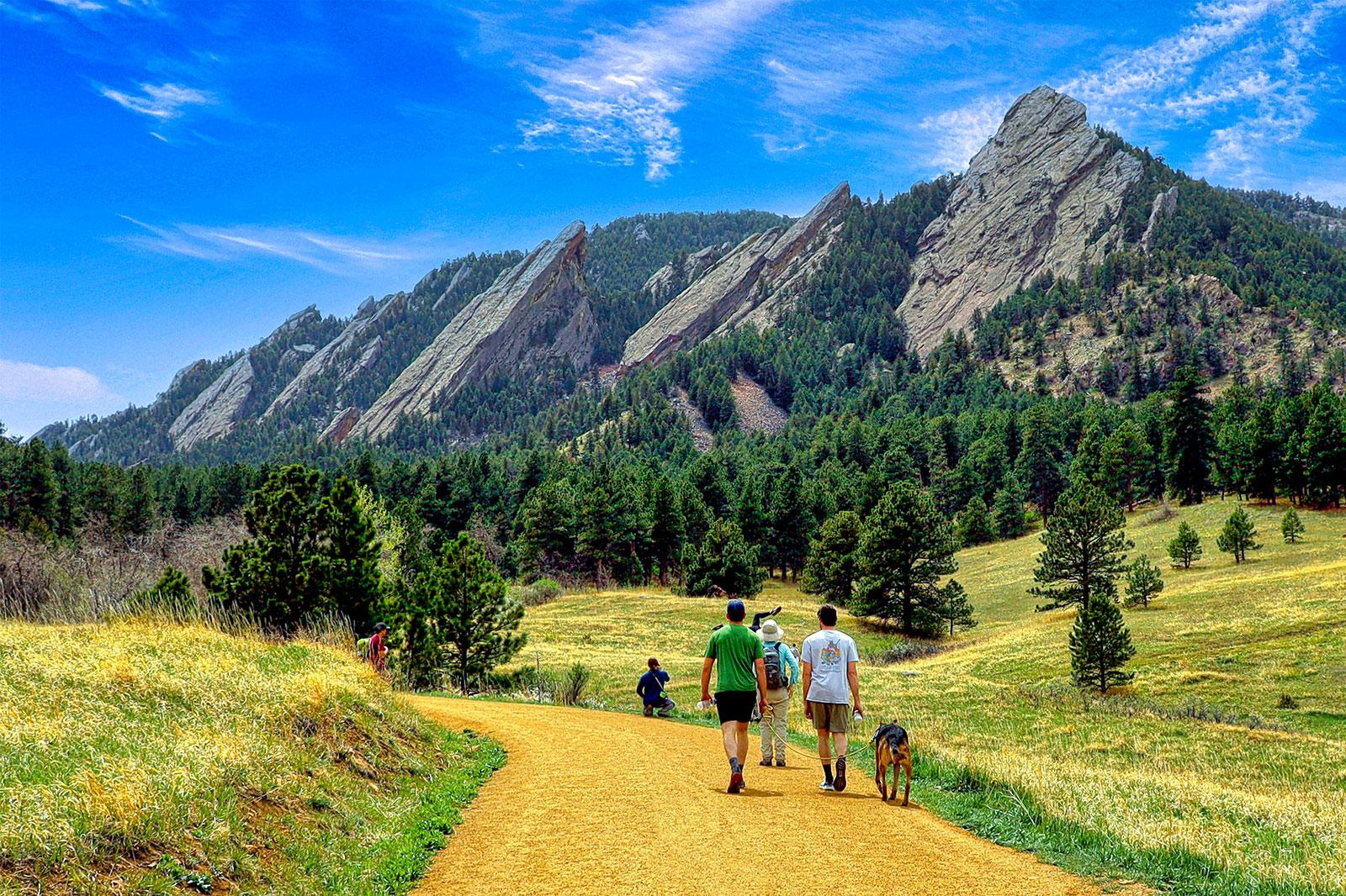 People hiking in front of mountains.