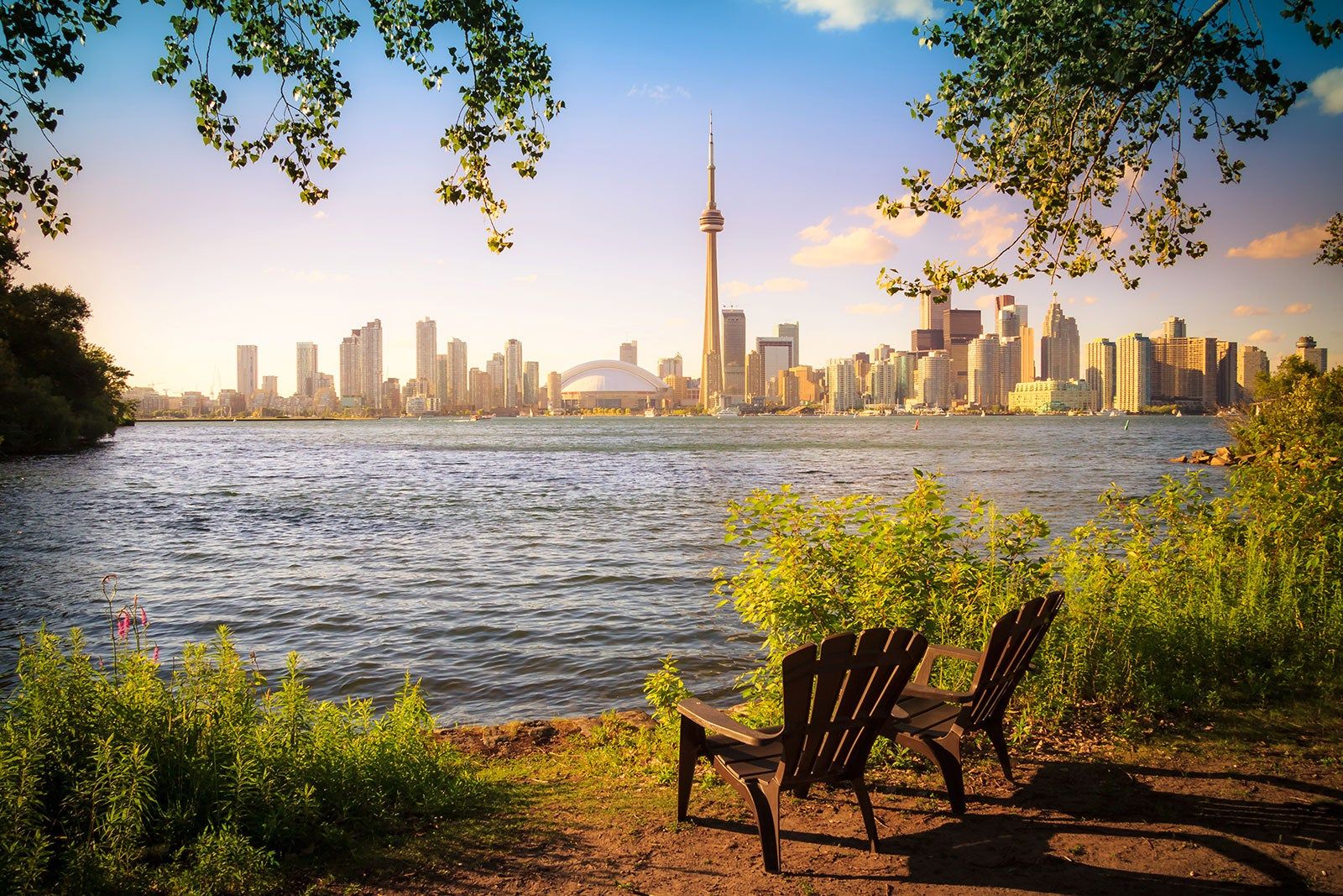 Two deck chairs by a body of water with the city skyline in the background.