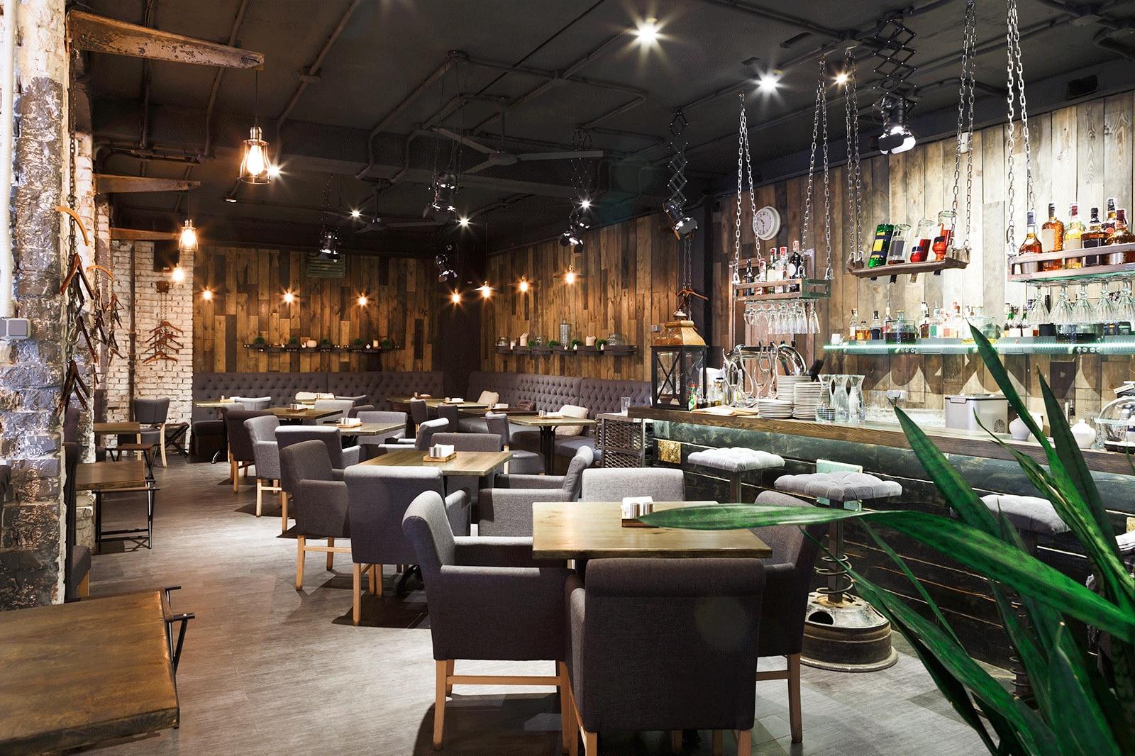 Classy restaurant interior with black chairs and a bar.
