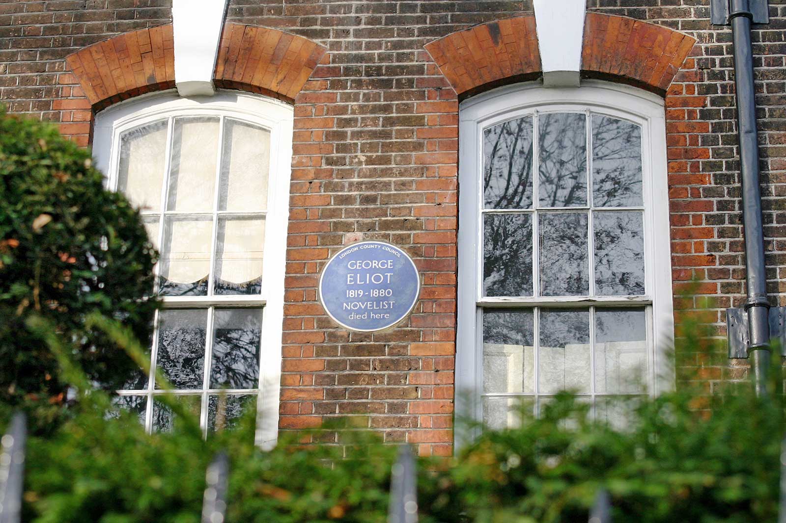 A round blue plaque on a house wall.