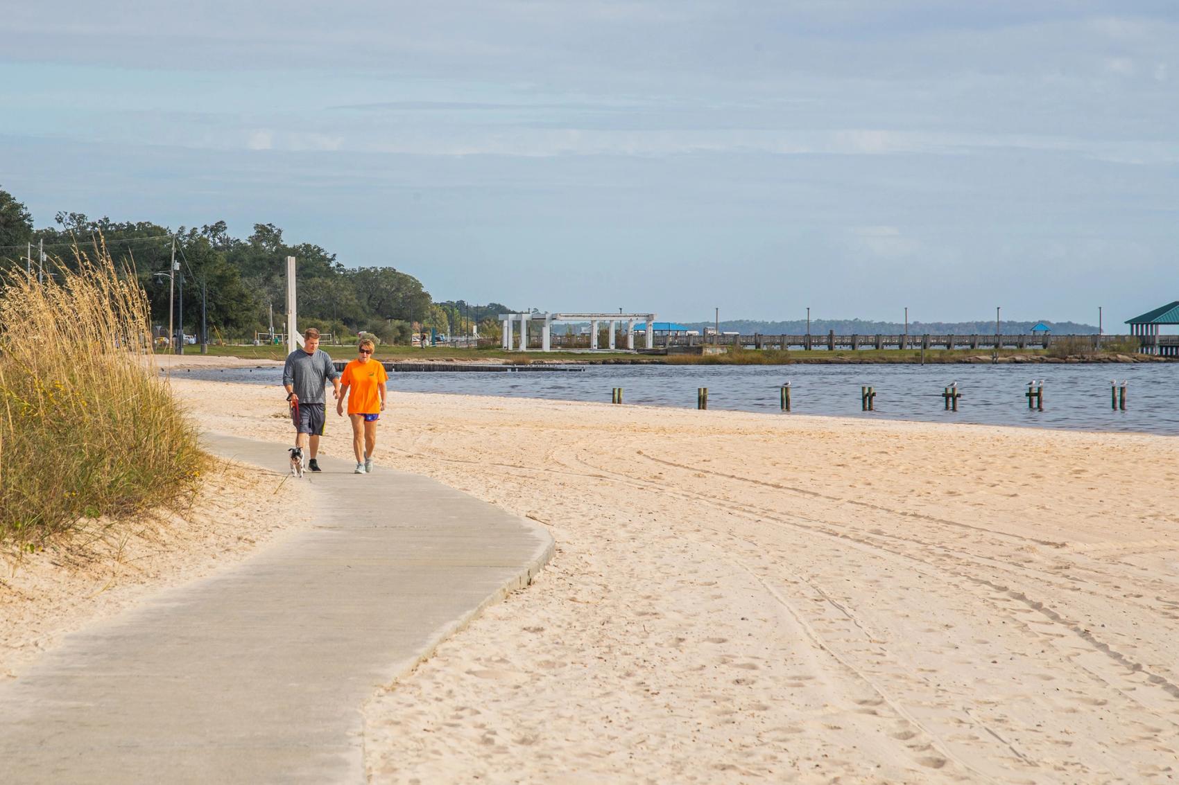 A couple walking their dog on a trail on the beach in Biloxi, Mississippi.