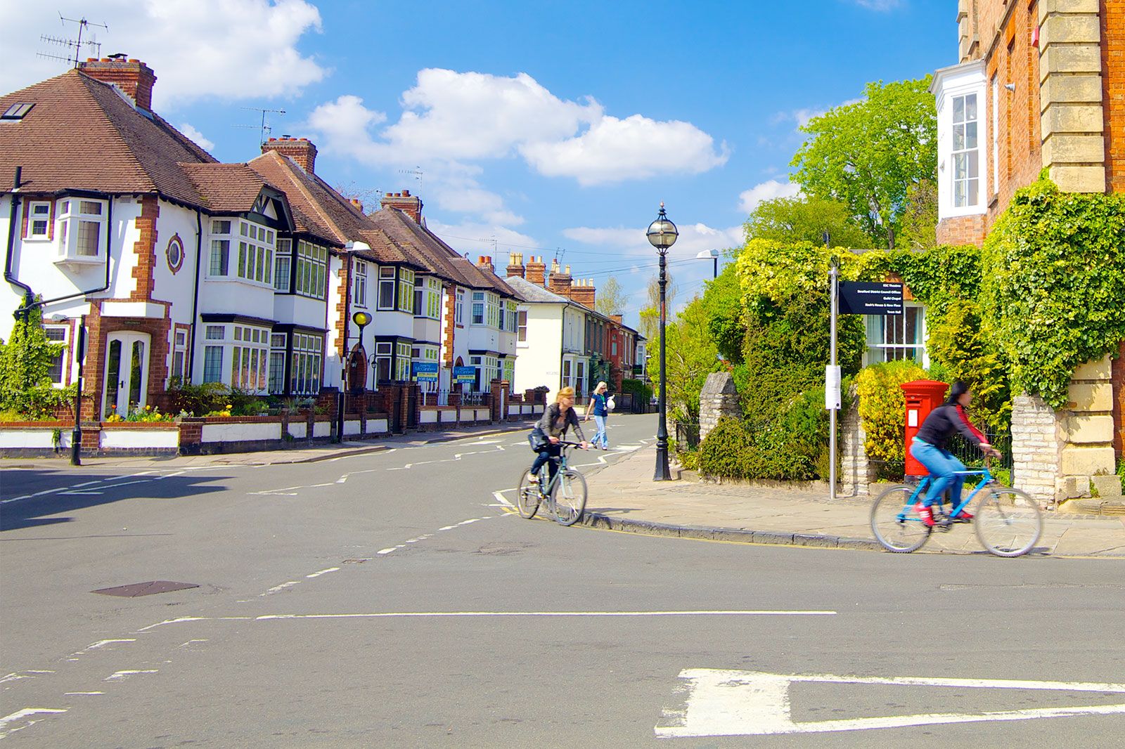 People ride bikes through an old town street.