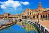 The Plaza de Espana square in Seville surrounded by a stately building and people rowing in the canal.