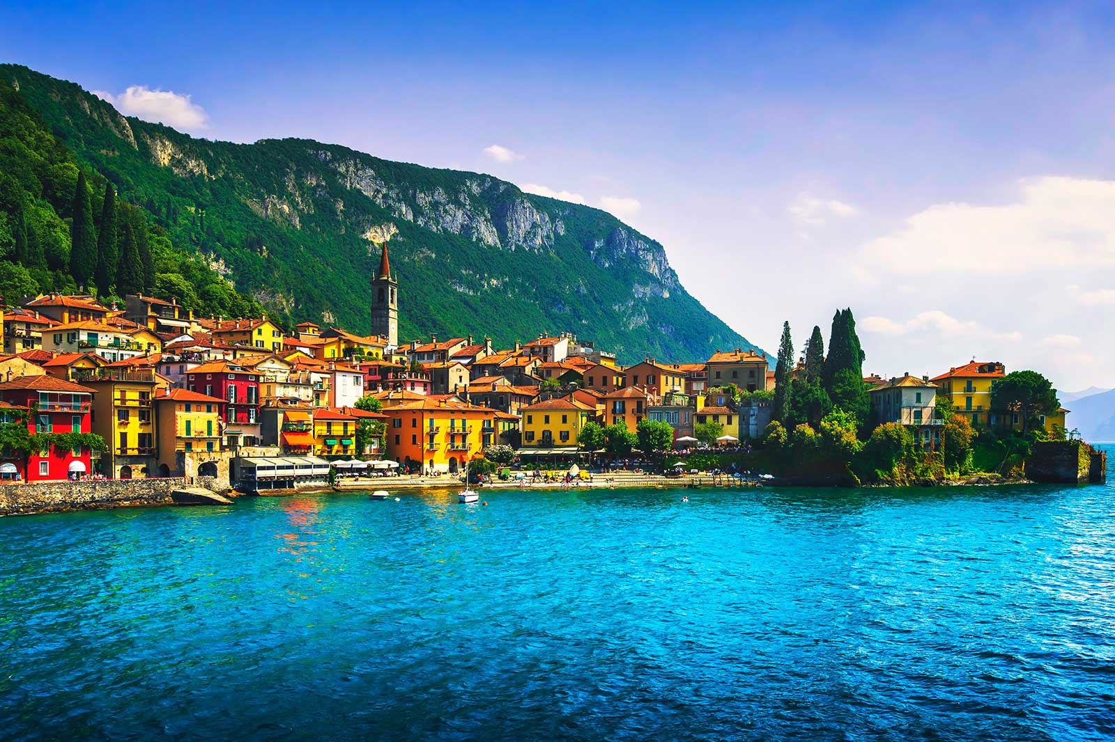 Colourful houses by a lake surrounded by a hill.