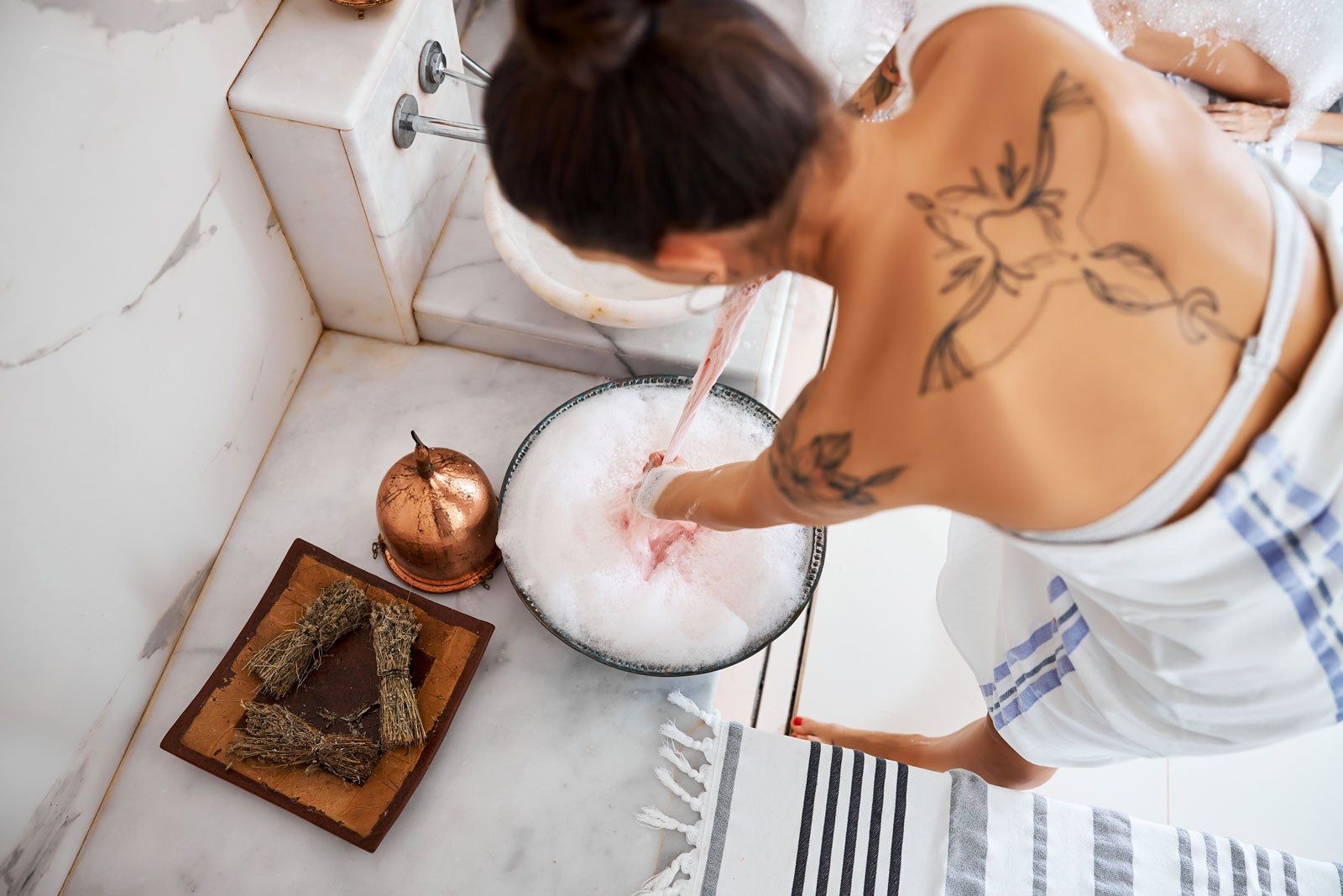 A person bathing in a spa with marble countertops. 