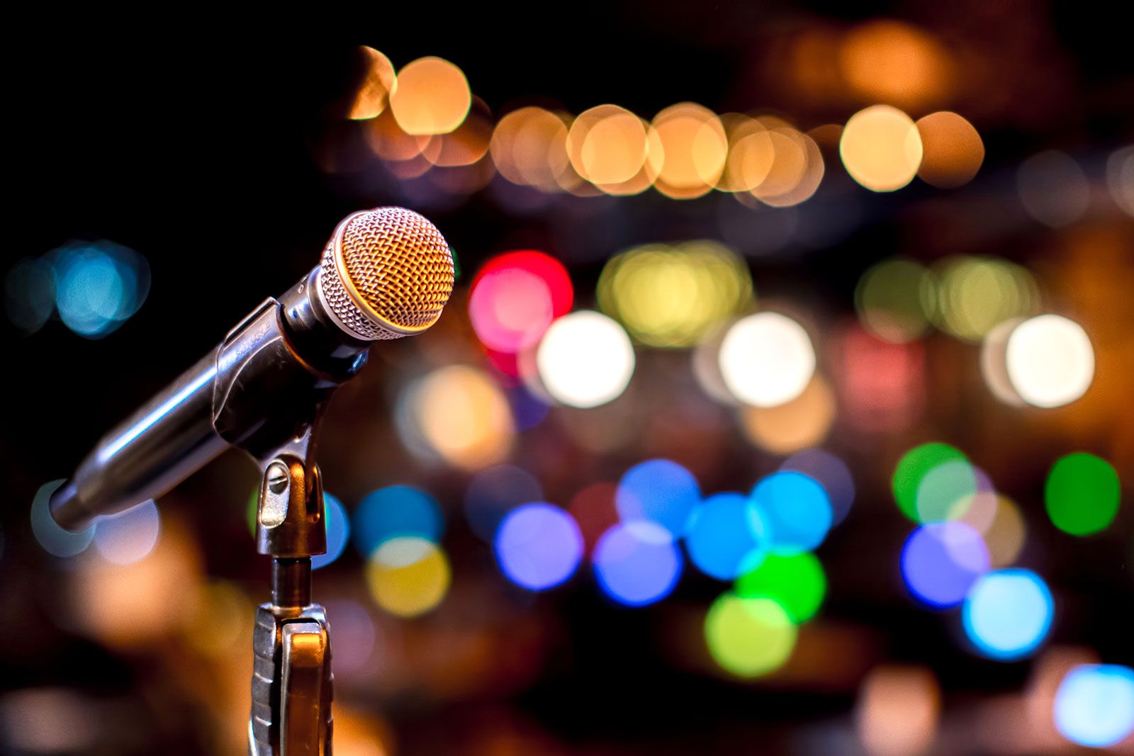 A mic with a stand on a colorful bokeh background.
