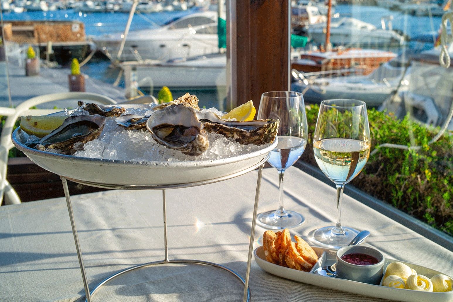 A raised dish with oysters on a table in a restaurant with sea view.