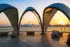 A beautiful view of Dubai city skyline through sculptures in the evening with a colorful sky.