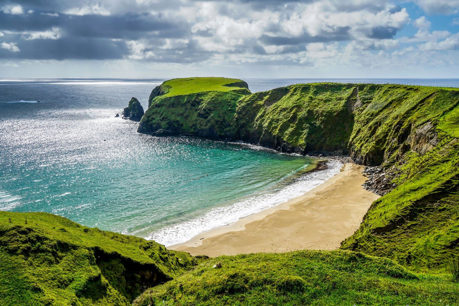 Beach, water and green cliffs.