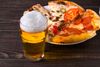 Beer and pizza on dark wooden background.