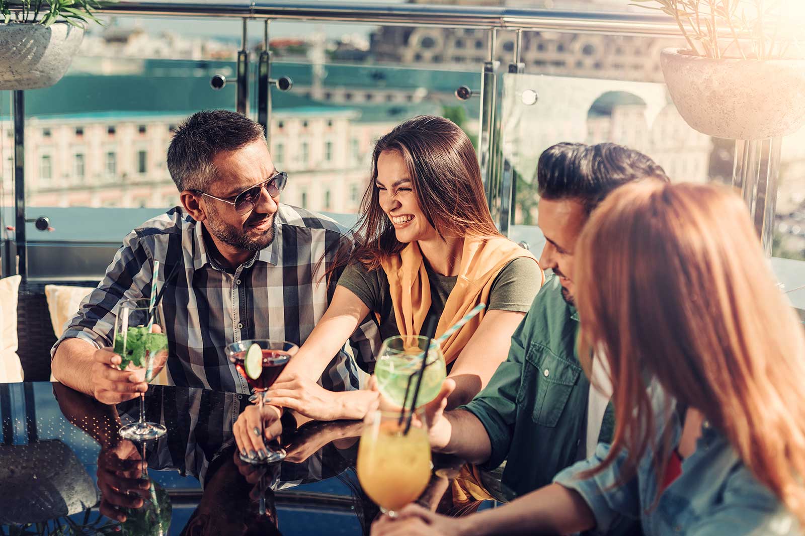 A group of people enjoying cocktails in a rooftop bar.