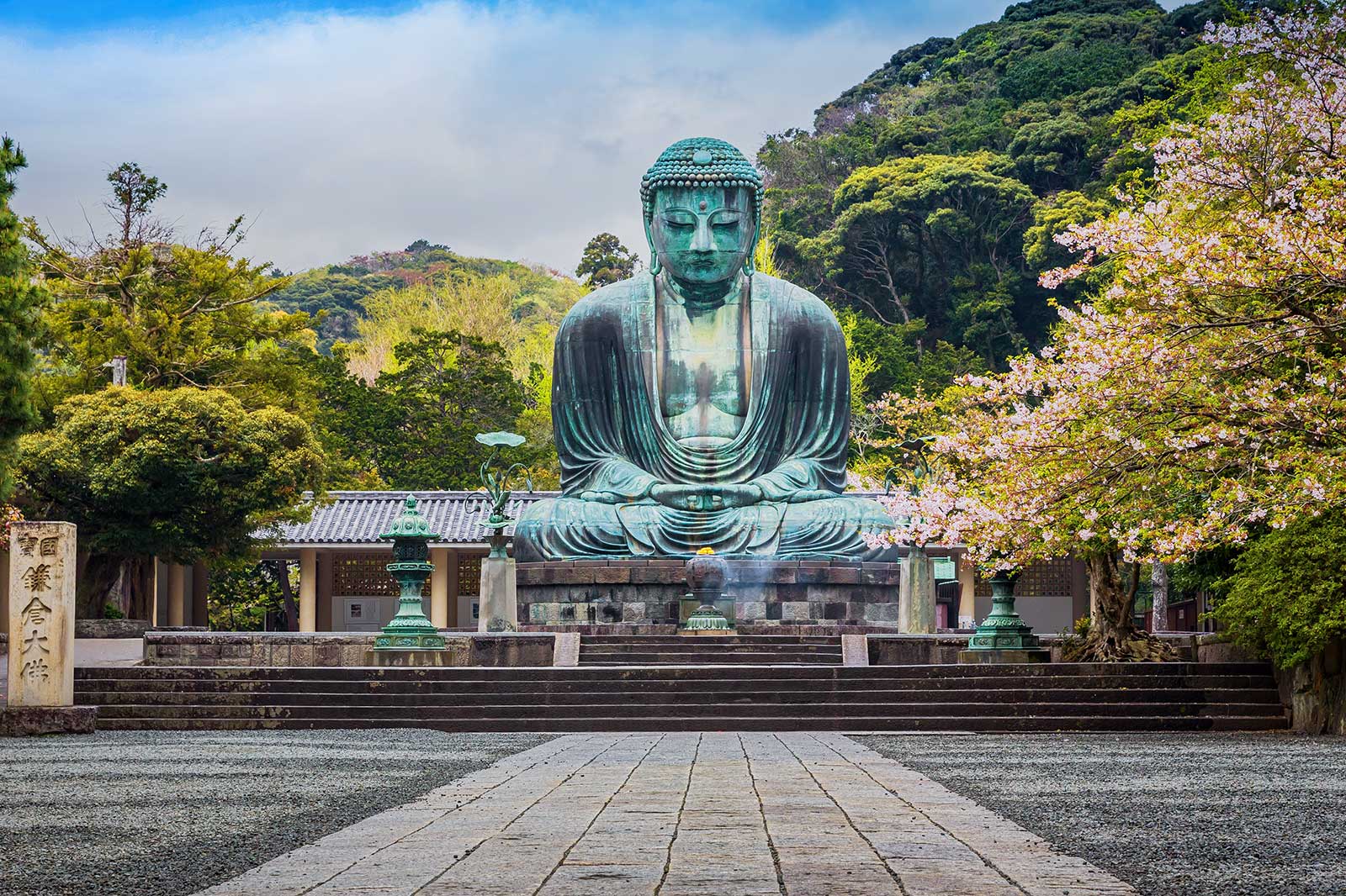 Statue of Buddha on a large square, trees in the background.