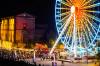 A ferris wheel is lit up at night during a festival.