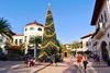 People walk around an outdoor shopping area with a Christmas tree.
