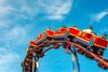 A group of people riding a roller coaster under the clear blue sky.