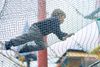 A child climbing over playground netting.