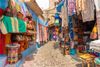 A traditional cobble street with colorful items for sale.