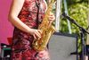 woman saxophonist playing at a jazz festival in a city park