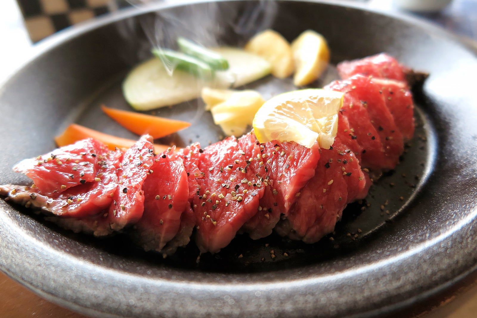 An elegantly plated dish of sliced steak with vegetable garnishes