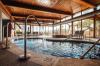 Indoor spa pool with gushing fountains and wood slatted ceiling and views of outside.
