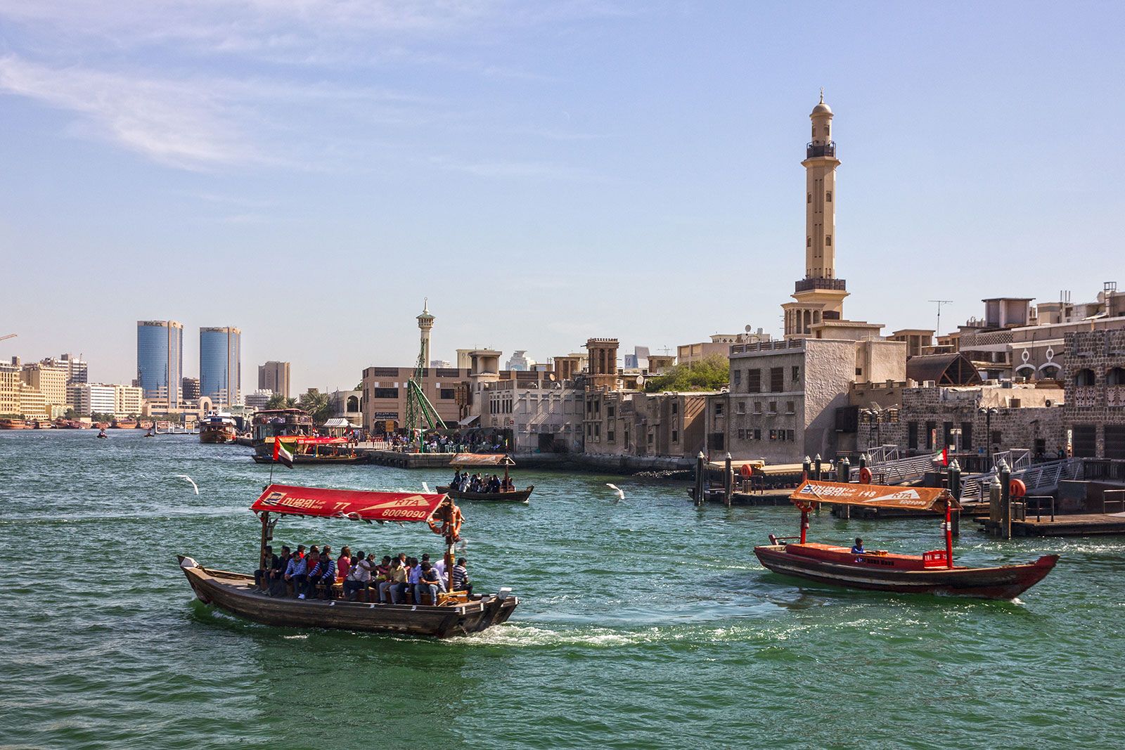 A couple of boats with people in a canal next to an old town.