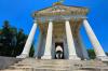 A grand stone memorial resembling a Roman pantheon, with a tall dome and columns, under a partly cloudy sky.