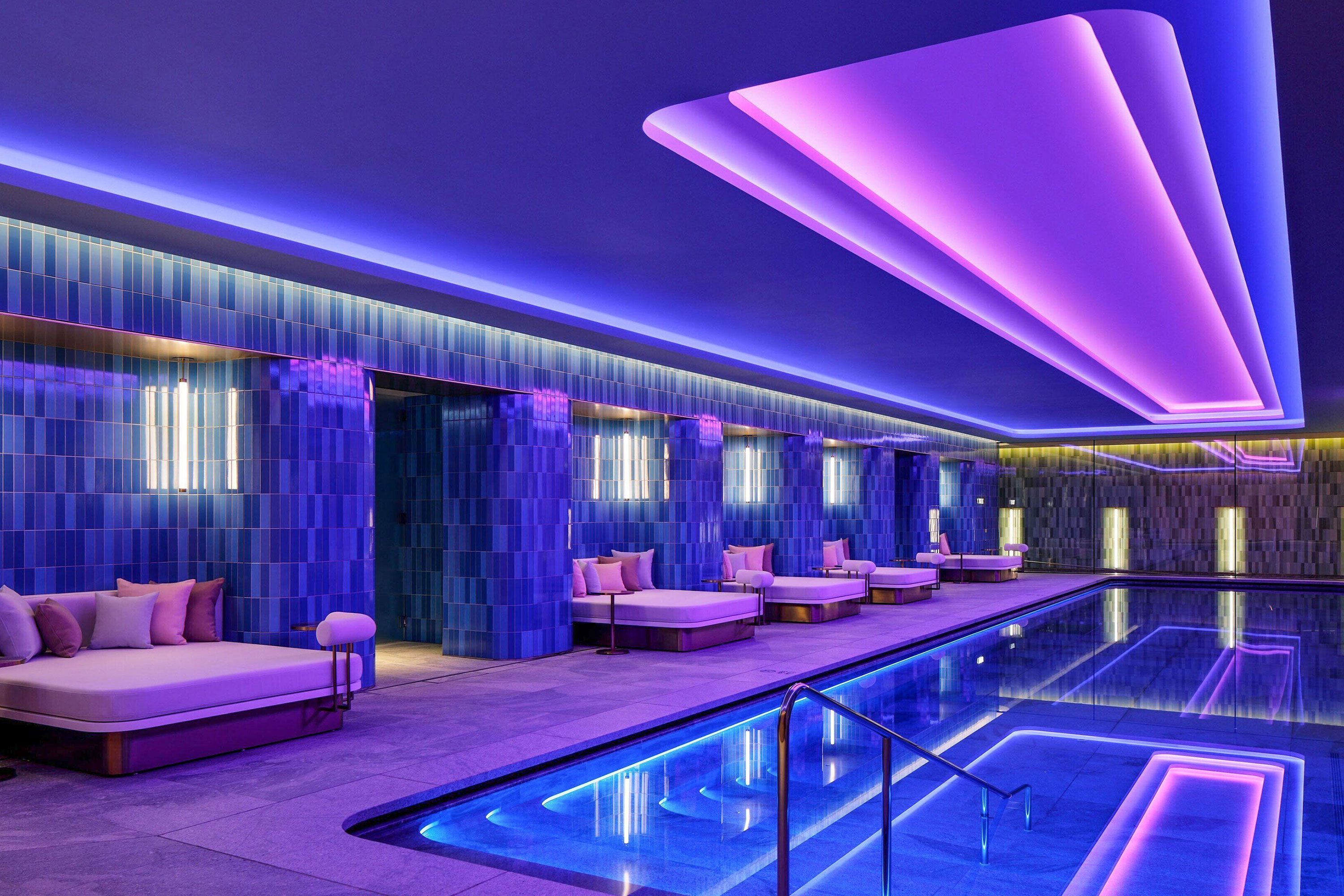 Neon lights illuminate an indoor pool.