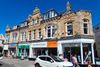photo by <a href="https://commons.wikimedia.org/wiki/File:Shops_on_Bank_Street,_Newquay,_Cornwall_-_June_2022_(4).jpg" target="_blank" rel="noreferrer">Mutney</a> (<a href="https://creativecommons.org/licenses/by-sa/4.0/" target="_blank" rel="noreferrer">CC BY-SA 4.0</a>)  modified