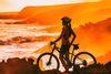 Female cyclist watching the ocean at sunset.