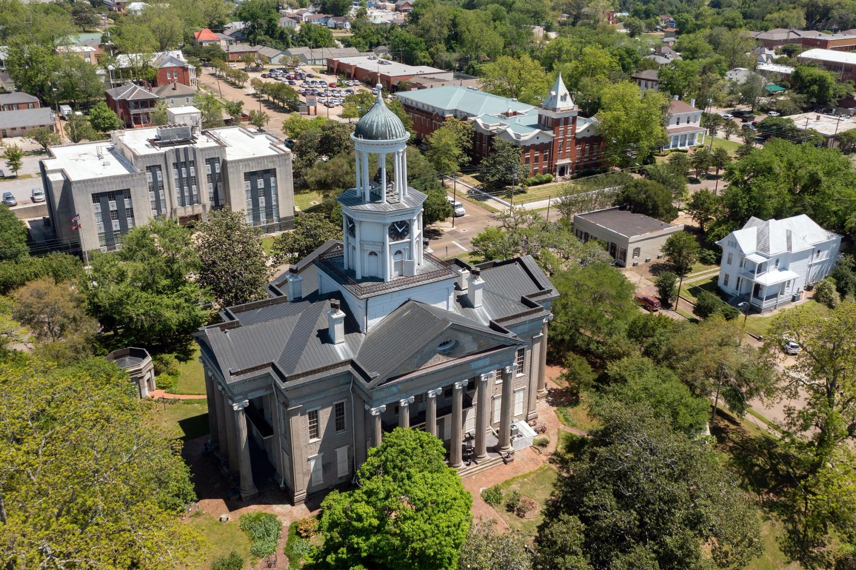 An aerial view of a courthouse bathed in afternoon sunlight, with surrounding downtown buildings.