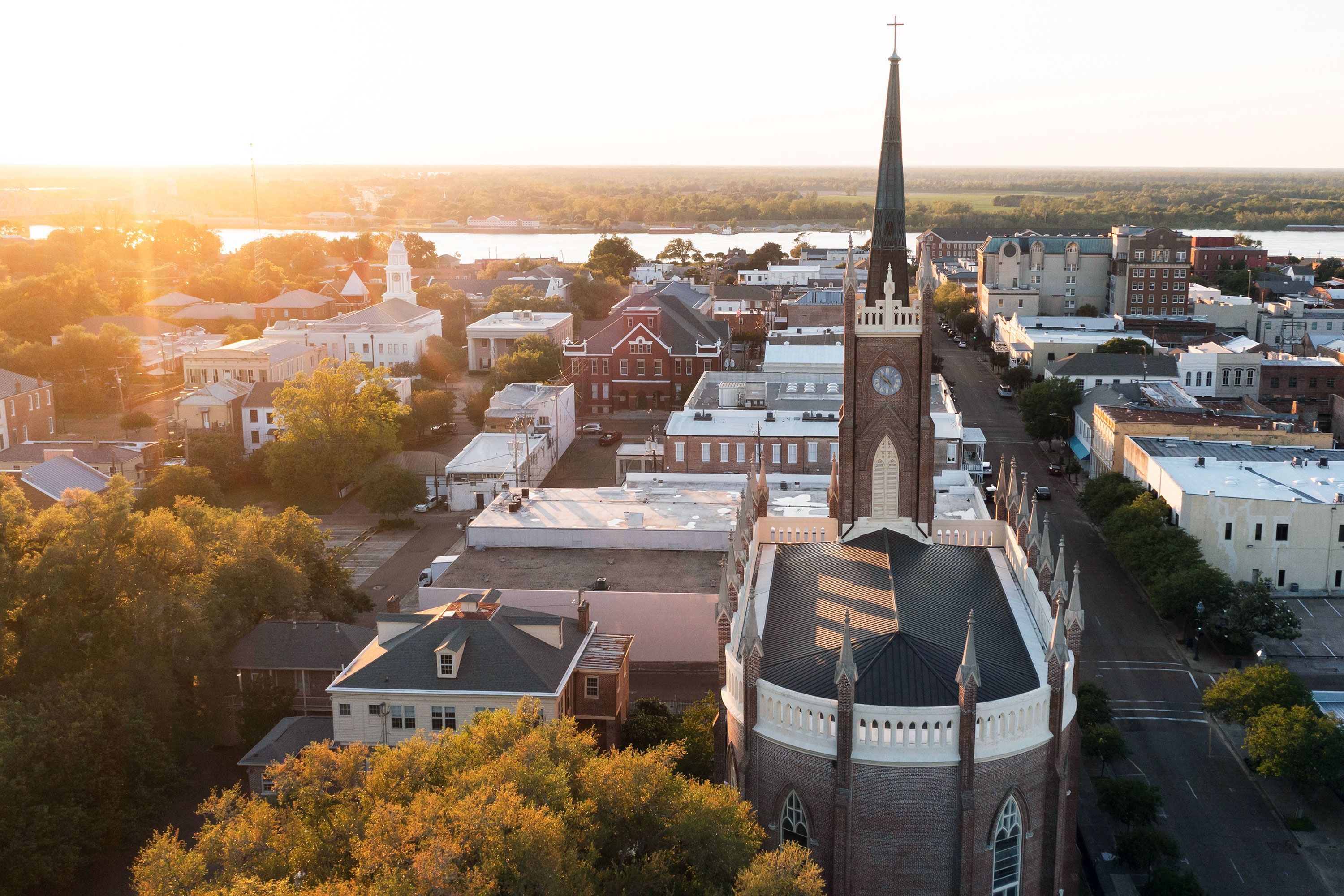 Golden sunset light illuminates a historic church building with surrounding downtown rooftops.