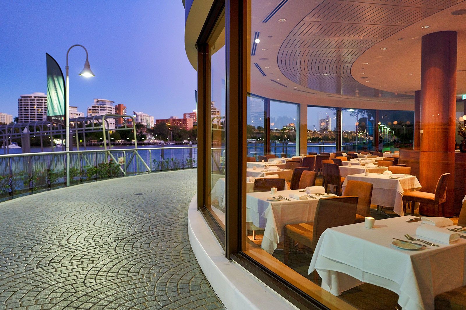 View of a restaurant interior, deck and the water in Brisbane.