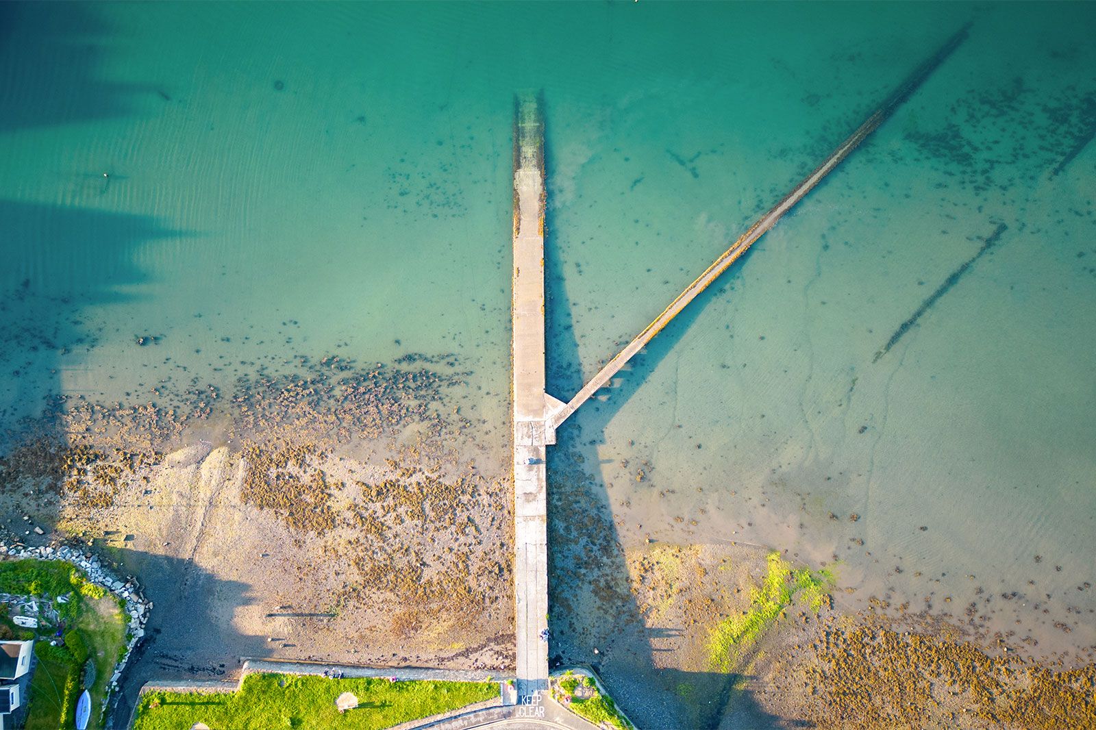 A pier disappears into an ocean shore.