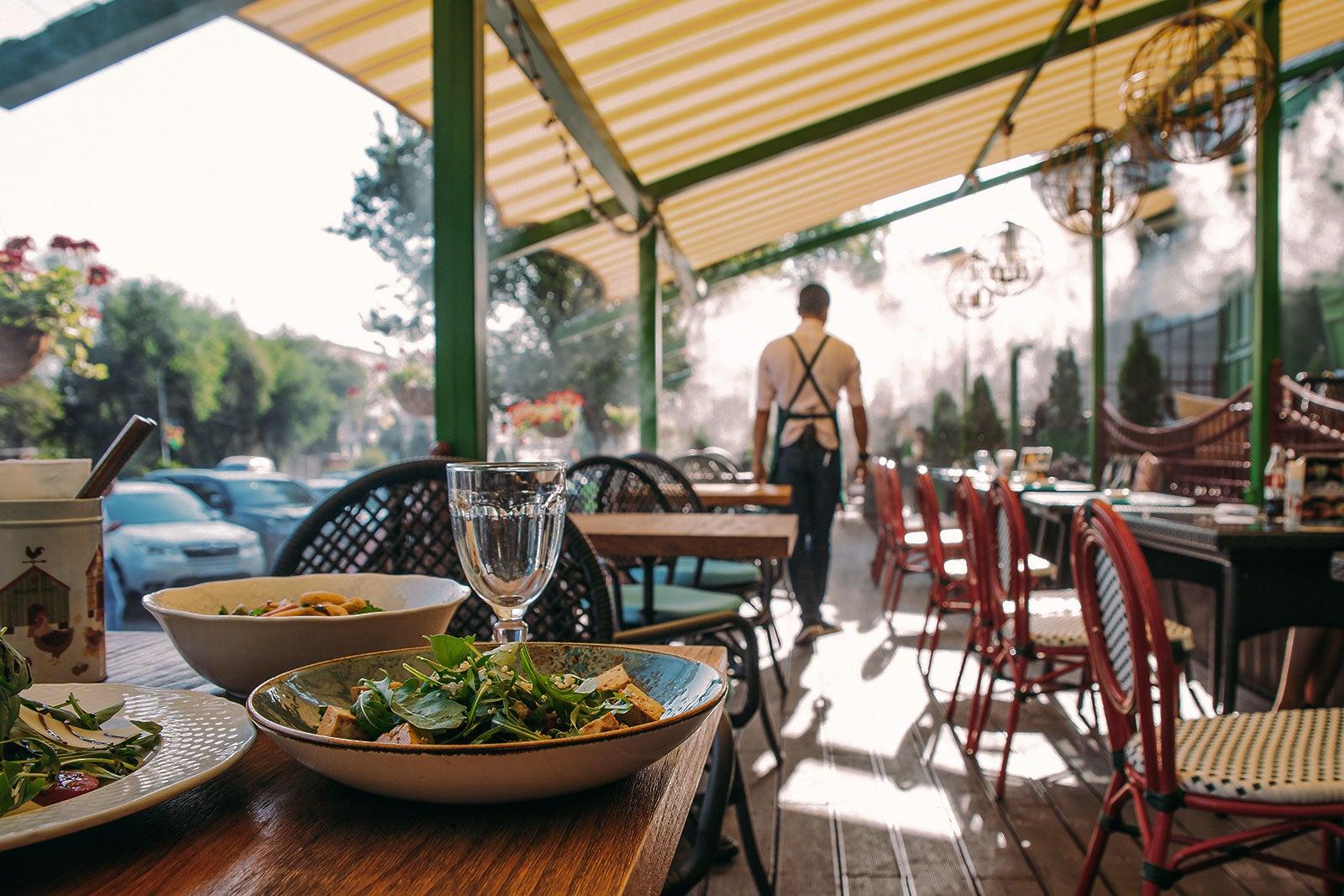 A table set for dinner with a waiter in the background.