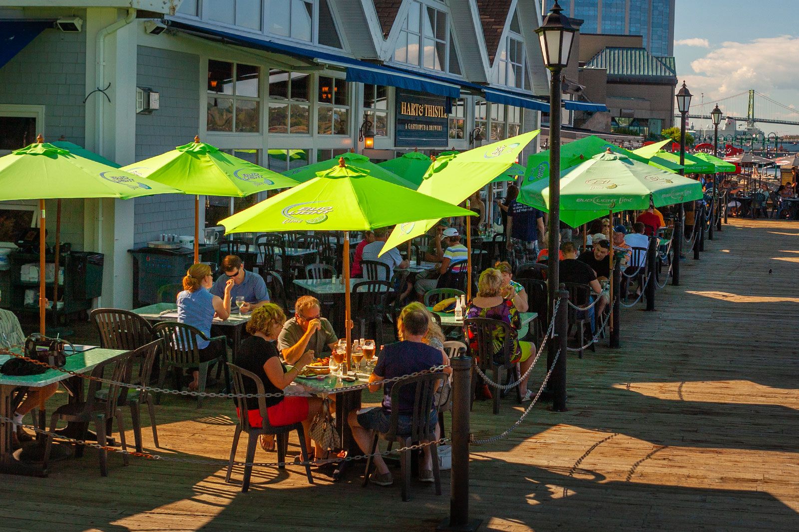 People sit outside under umbrellas eating at a restaurant . 