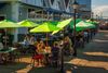 People sit outside under umbrellas eating at a restaurant .
