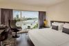 A modern room with a bed and chair, and a view over the Thames River.