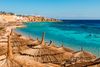 A bright blue beach with umbrellas.