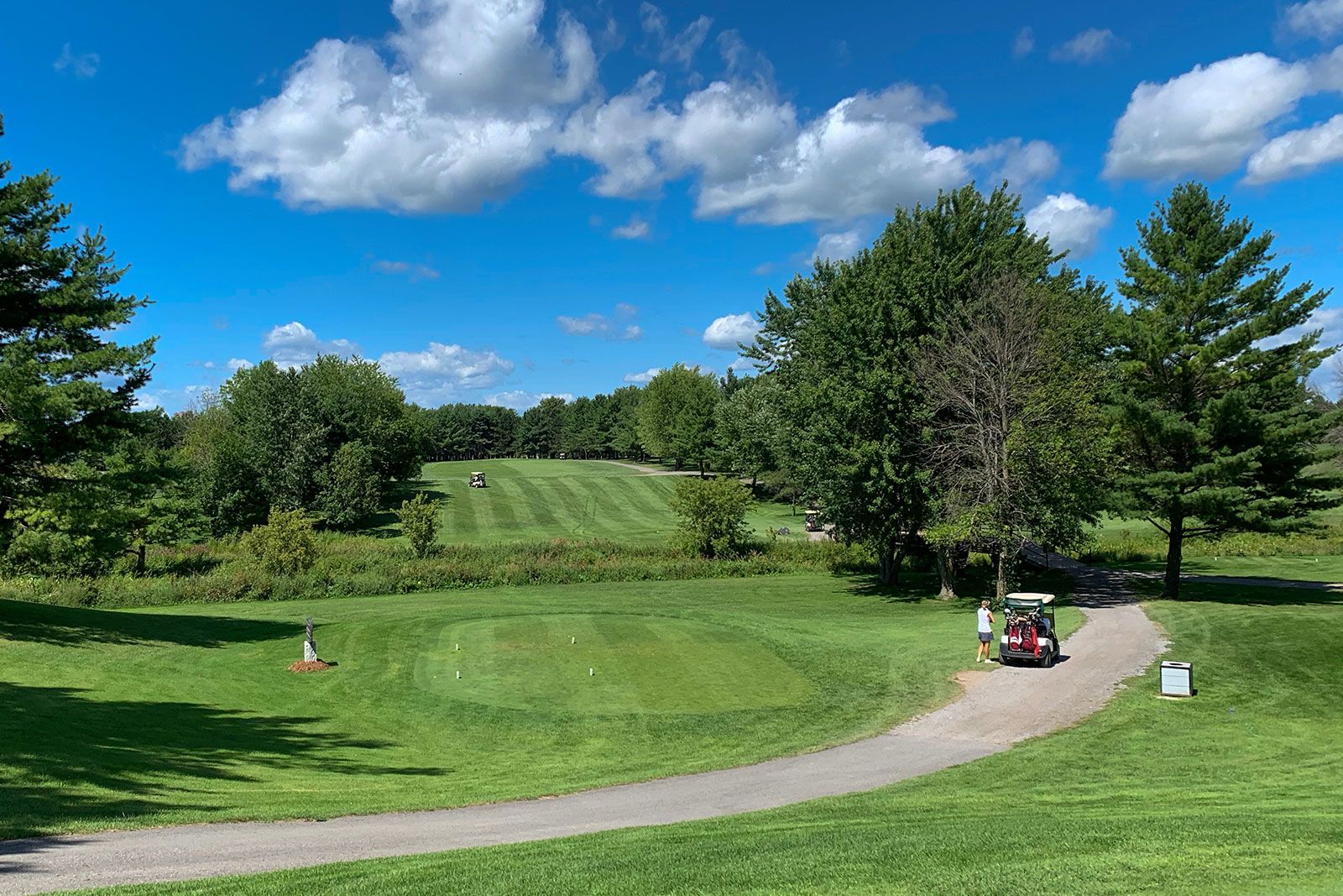 A green golf course and blue cloudy sky on a beautiful summer day in Canada.