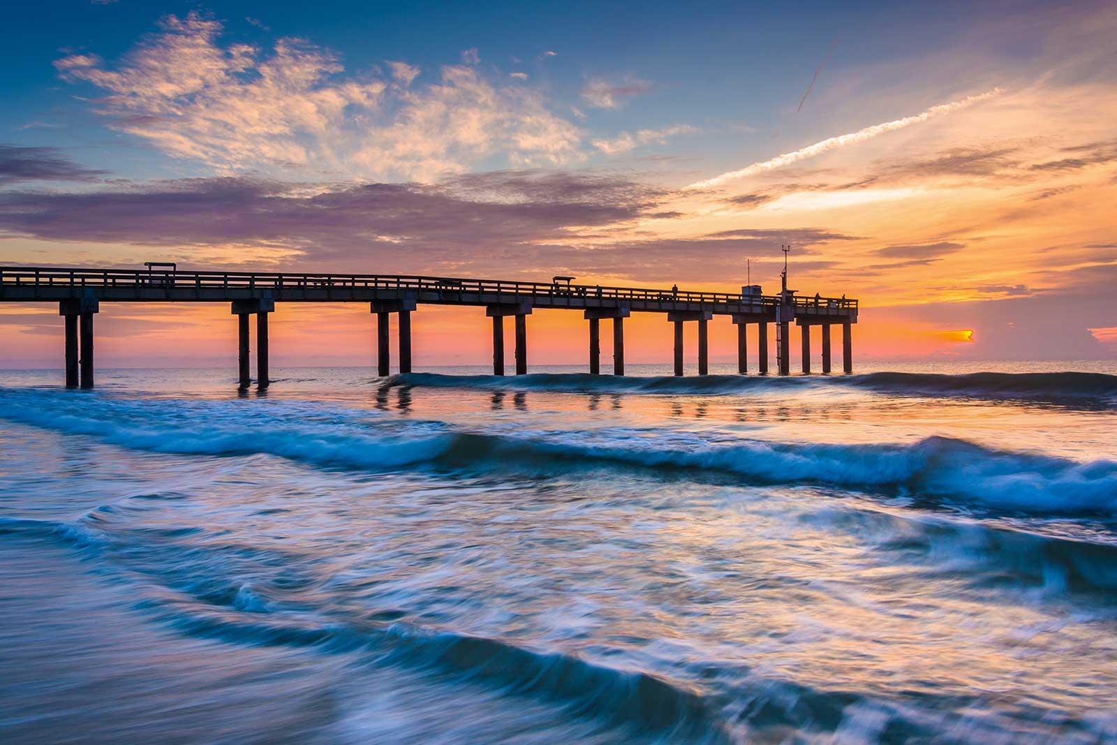 Pier at sunset with waves.
