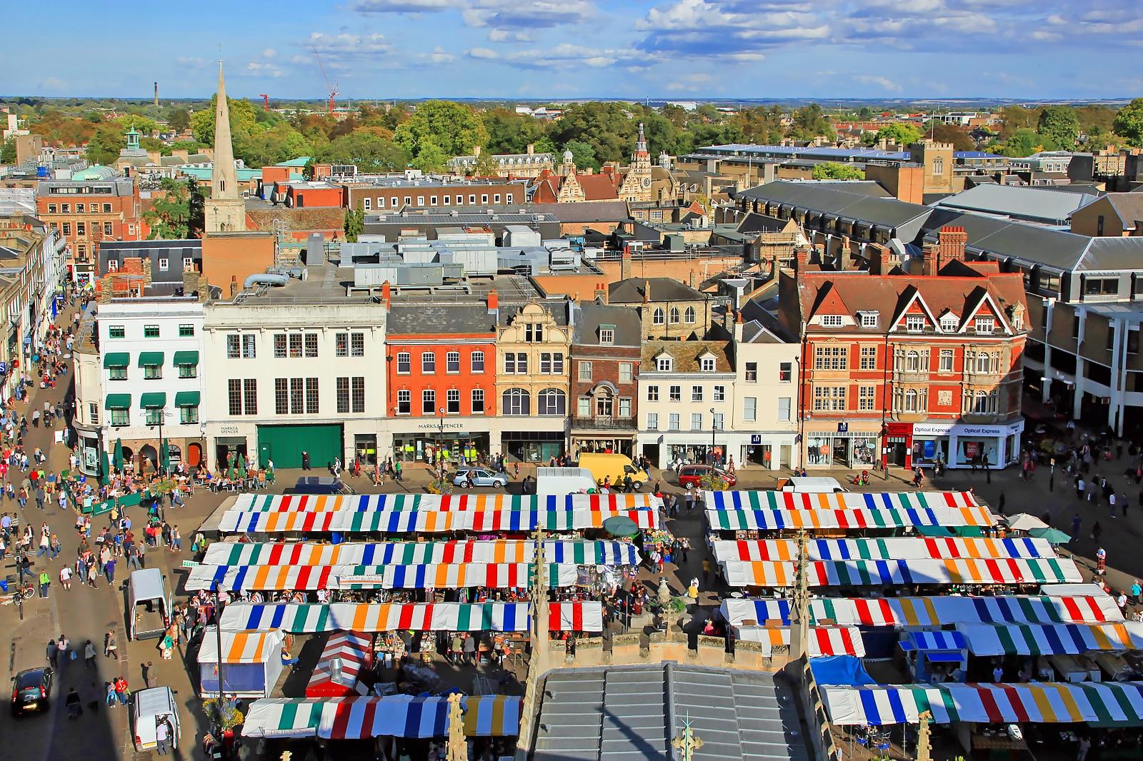 Colorful buildings with outdoor vendors and shoppers at market.