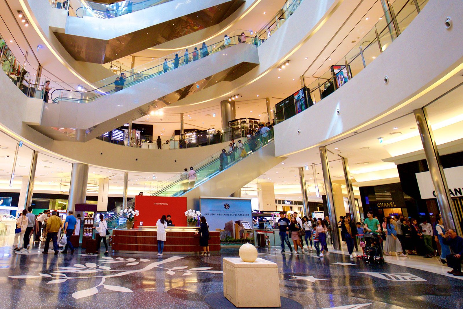 An interior of a shopping mall with shoppers scattered around. 