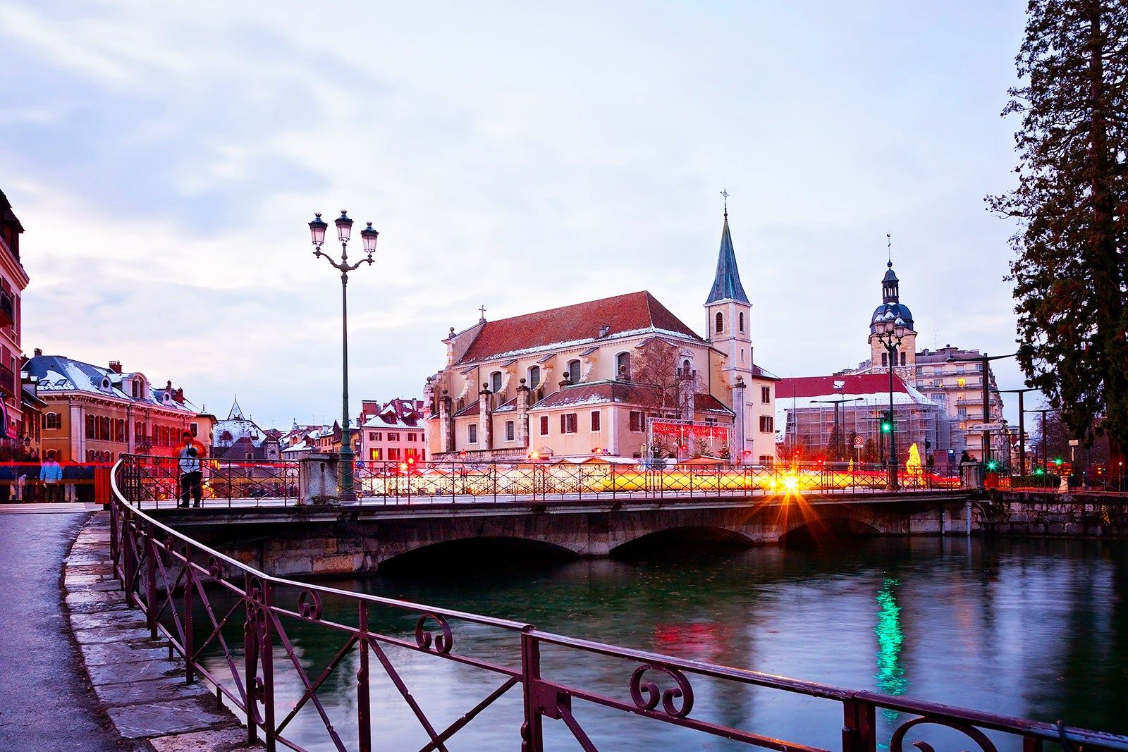 A view of a river with a bridge across it and a town in evening lights in the background.