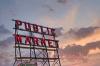 A neon sign for the Pike Place Public Market in Seattle at sunset..