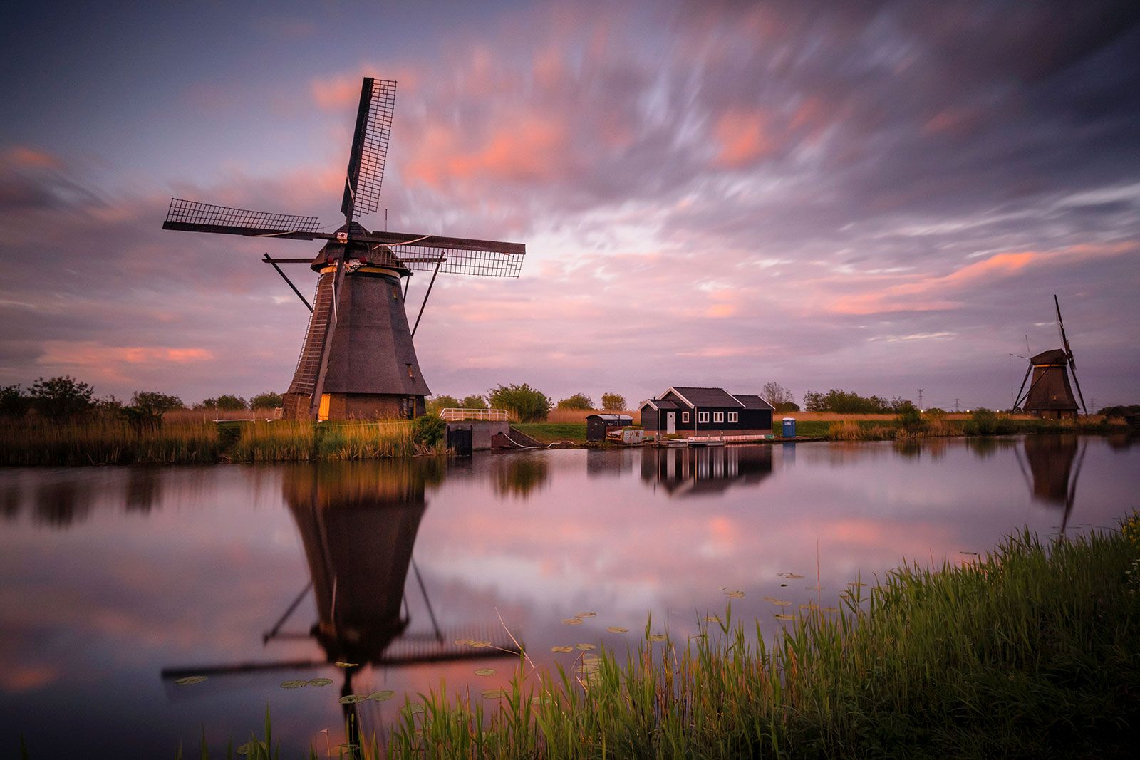 An old windmill at sunset near water.